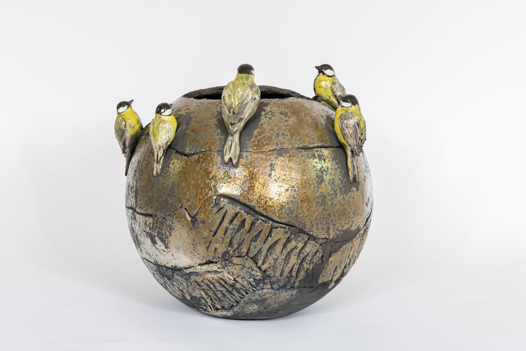 on y voit un vase en céramique avec des oiseaux sculptés